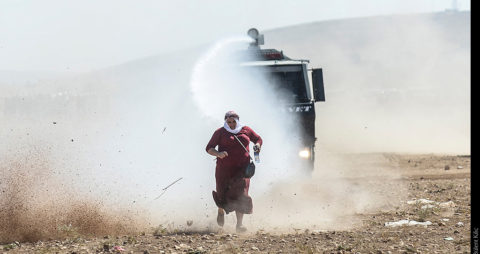 A Kurdish woman runs away from a water cannon near the Syrian border after Turkish authorities temporarily closed the border at the southeastern town of Suruc in Sanliurfa province, on September 22, 2014. Tens of thousands of Syrian Kurds flooded into Turkey on Saturday, fleeing an onslaught by the jihadist Islamic State group that prompted an appeal for international intervention. AFP PHOTO/BULENT KILIC