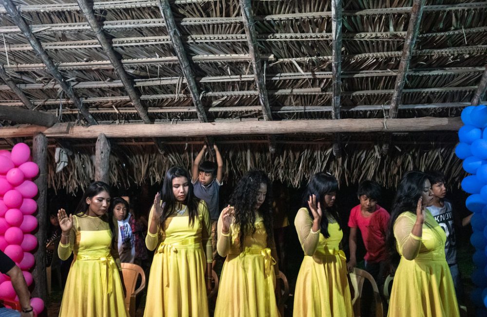 Indigenous girls from Krikati Etnicity pray during a birthday at Sao Jose Krikati tribe, Maranhao state, Brazil. The Krikati ethnicity has been growing its evangelical population in the last 10 years. CONPLEI, Conselho Nacional de Pastores e Lideres Evangelicos Indigenas (National Council of Pastors and Evangelical Indigenous Leaders) is the organization responsible for organizing and mobilizing the "Third Missionary Wave". This wave is a movement that aims the conversion of indigenous made by other indigenous, instead of Europeans or white Brazilians. Ian Cheibub/GEO MAGAZINE, November 24, 2022.