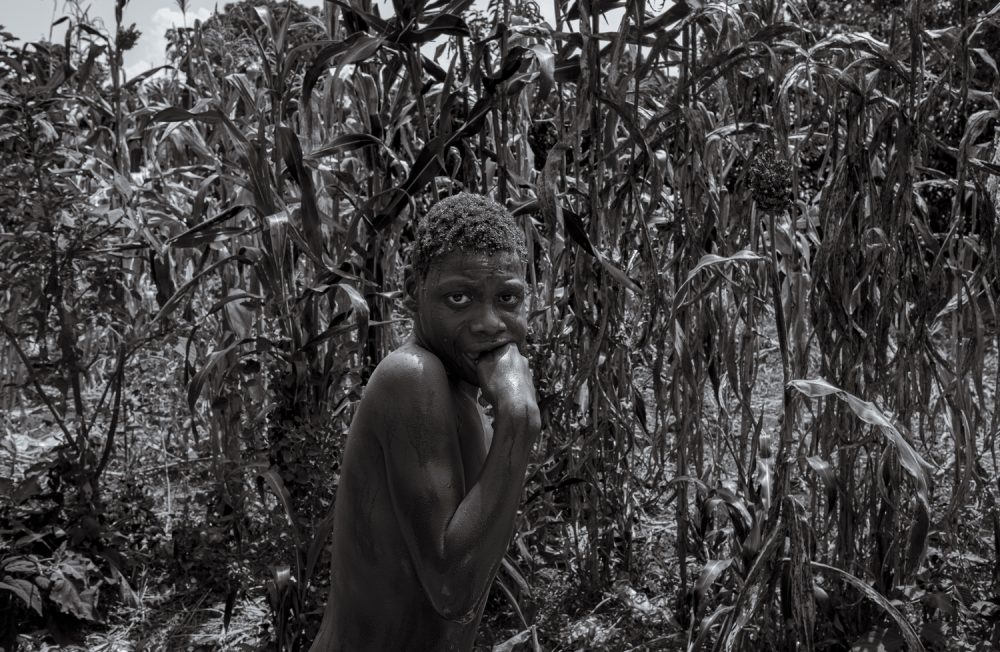 19 July 2023. Nabwigulu, Kamuli District, Uganda.  Perez Mwase cowers in the family maize field after being bathed by his mother Lovinsa Namwebya. 
19-year-old Perez lives with severe, category four, autism. Lovinsa tried for years to have her son’s condition diagnosed. Unable to deal with his aggression and hyperactivity, his parents tied him to a tree for 11 years. He was fed and toileted in the same place until late evening when he would join the family inside. Following the death of his father from suicide, Lovinsa struggled to care for Perez alone and he was moved to the Amaanyi Centre, a home and school for children with intellectual disabilities run by NGO Embrace Kulture, a two-hour drive away in Entebbe. While there he was formally diagnosed with severe, category four, Autism. 

In November 2017 the family instigated a case challenging the Ugandan government and the Buyende Local Government with failure to provide early detection, rehabilitation, and habilitation services at the primary health care level for a person living with Autism. In a landmark decision in March 2022 the court ruled in favour of Perez on all counts.  The court found that the government’s failure amounted to a violation of his human rights; his right to health, right to equality and freedom from discrimination, and his right to human dignity provided for under the 1995 Constitution of the Republic of Uganda.